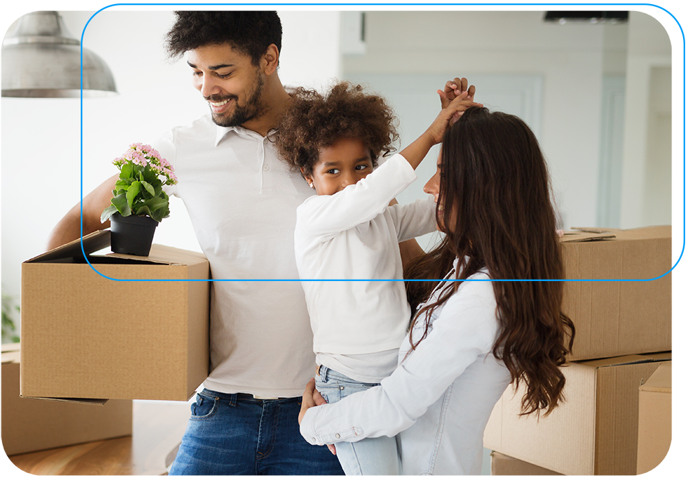 Couple with young child moving boxes into their newly purchased home with potted flower